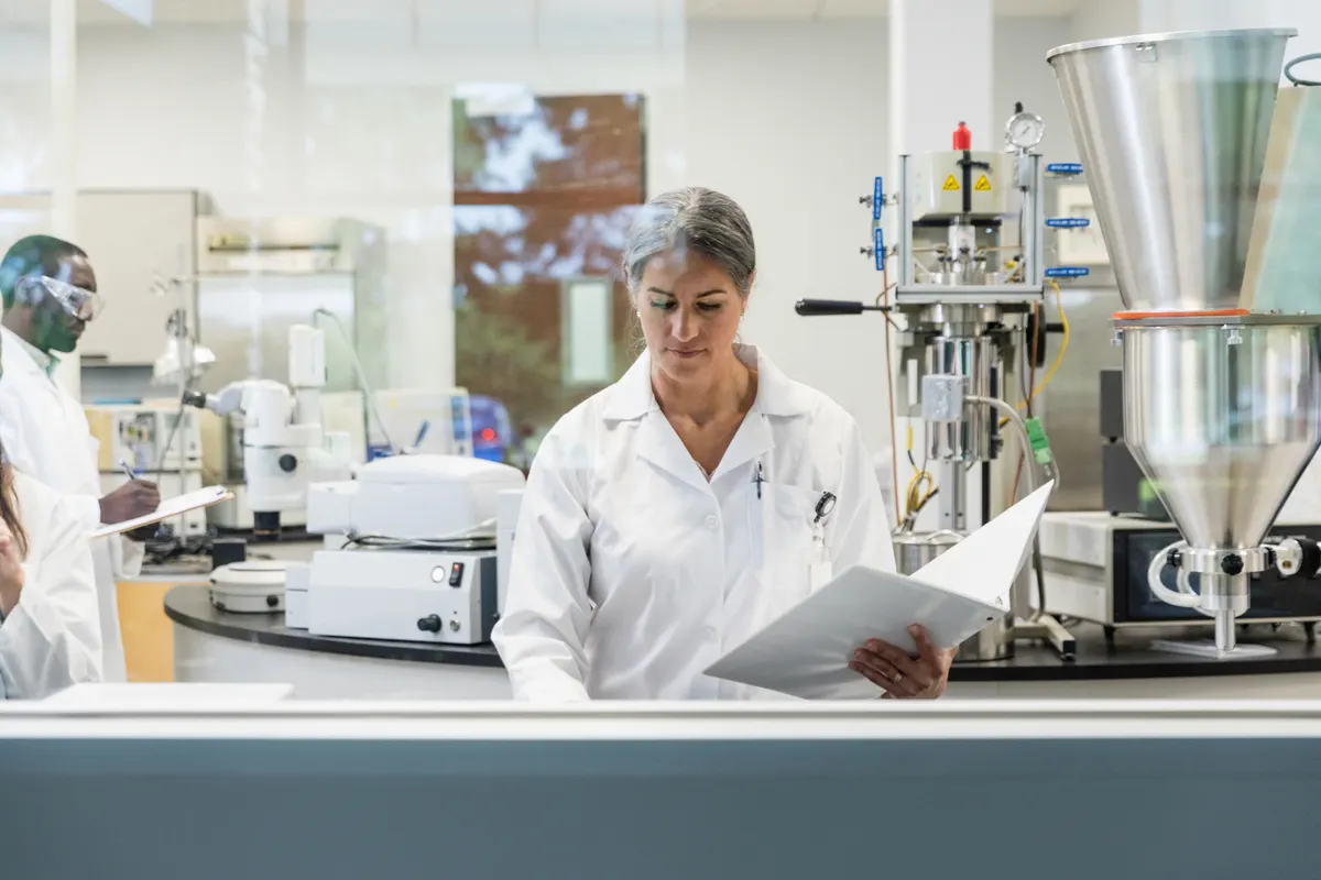 A scientist in a laboratory reading a binder of documentation
