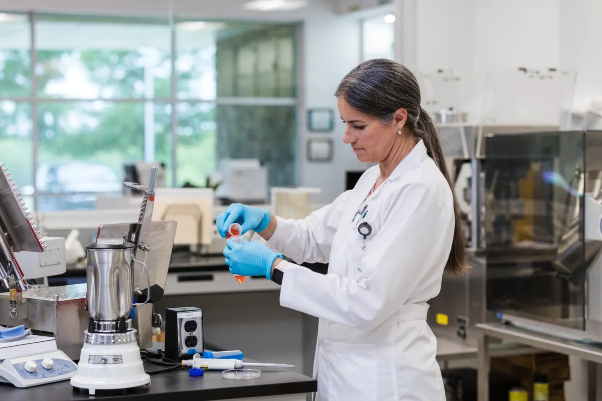 A laboratory technician carefully mixing solutions at a formulation bench